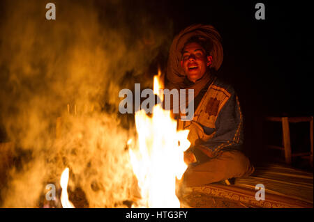 Un nomade uomo berbero cantando accanto a un fuoco di campo nel deserto del Sahara, Marocco Foto Stock