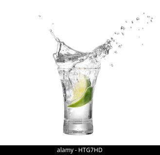 Colpo di vodka o tequila con fetta di lime e splash isolati su sfondo bianco. È la calce che rientrano nell'alcool bere. Splash di vodka dalla caduta Foto Stock