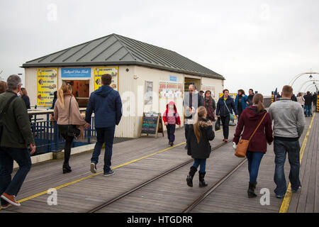 Famiglie che camminano sul molo a Southport, Merseyside, Regno Unito. Meteo Regno Unito. 11th marzo 2017. Noioso, ma caldo come passeggini godere le temperature che raggiungono doppie cifre e prendere l'aria di mare sul molo di Southport Iron Pier. Il punto di riferimento vittoriano è una grande attrazione per i visitatori del resort in quanto assume un aspetto di inizio estate con tram stradale in funzione e bancarelle di Donut in piena produzione. Credit; MediaWorldImages/Alamy Live News Foto Stock