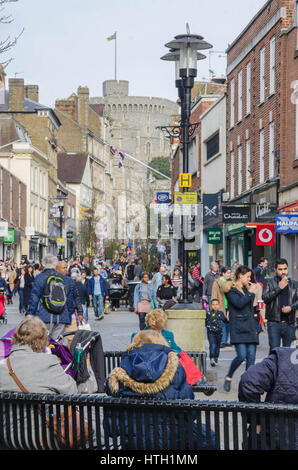 Ricerca peascod street in Windsor. Il castello di Windsor è in distanza. persone sedersi sulle panchine in strada per un riposo. Foto Stock