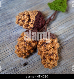 Bella artigianale di ornamento per le vacanze invernali, gruppo di maglia Xmas Pigna, holly leaf, bacche lavorato a maglia di filati, messaggio Buon Natale su tag Foto Stock