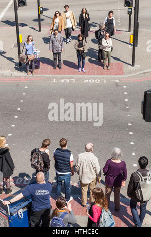 Le persone in attesa di attraversare la strada, London, England, Regno Unito Foto Stock