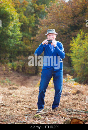 Un vecchio uomo di scattare una foto con la vecchia pellicola compatta fotocamera Foto Stock