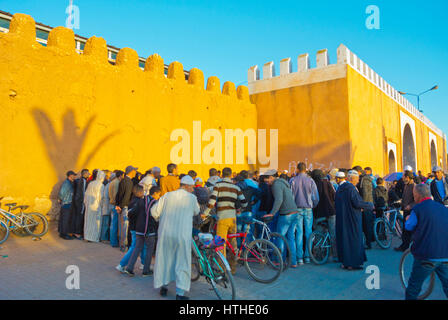 Gli uomini guardando una street performance, un serpente incantatore, al di fuori delle pareti di medina, Tiznit, Souss Massa regione, Marocco Foto Stock