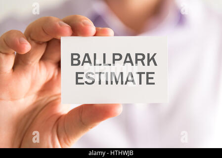 Primo piano sul proprietario in possesso di una carta con BALLPARK messaggio stima, business Concetto di immagine con messa a fuoco morbida dello sfondo Foto Stock