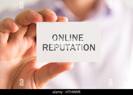 Primo piano sul proprietario in possesso di una carta con reputazione online messaggio, business Concetto di immagine con messa a fuoco morbida dello sfondo Foto Stock