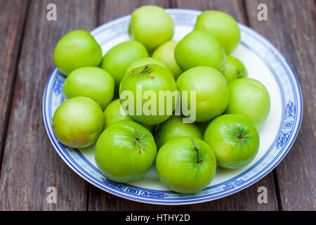 Mele Verdi. Monkey apple sweet frutta asiatica su piastra ceramica. Sfondo di legno. Foto Stock