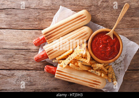 Grigliata di hot dog panini con patatine e salsa di pomodoro vicino sul tavolo. vista orizzontale dal di sopra Foto Stock