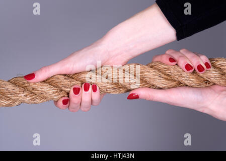 Donna con le mani le unghie verniciate di presa di una fune Foto Stock