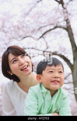 Giapponese madre e figlio con fiori di ciliegio in un parco della città Foto Stock