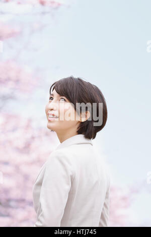 Donna Giapponese con fiori di ciliegio in un parco della città Foto Stock