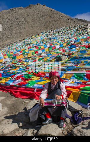 Nomade tibetana pellegrino donna seduta su roccia, tenendo la preghiera di perline in mano a Dolma La top en route Mt. Kailash Kora Foto Stock