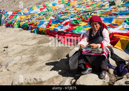 Nomade tibetana pellegrino donna seduta su roccia, tenendo la preghiera di perline in mano a Dolma La top en route Mt. Kailash Kora Foto Stock