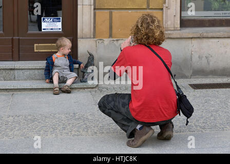 Padre tenendo la foto del figlio in una piccola scultura di gnome al Rynek (Piazza del Mercato) a Wroclaw, Bassa Slesia, Polonia Foto Stock