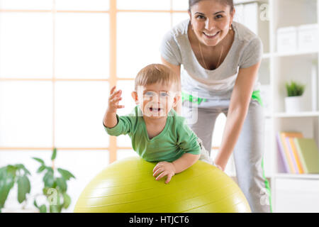 Felice madre e il suo bambino sulla sfera di fitness. Gimnastics per bambini su fitball. Foto Stock