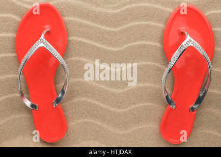 Coppia di red sandali da spiaggia in strass stand sulla sabbia. Vista da sopra Foto Stock