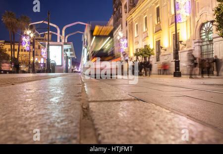 Il tram che corre lungo il centro di notte con decorazione di Natale, Siviglia, Spagna. Il movimento sfocato Foto Stock