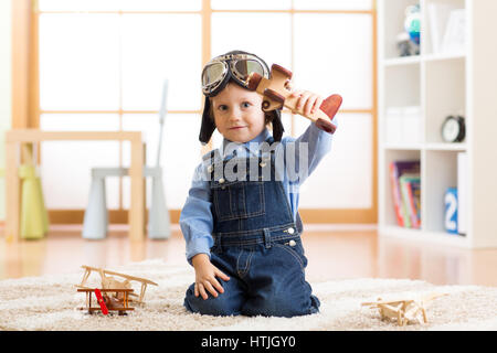 Bambino fingendo di essere aviatore. Kid giocando con gli aeroplani giocattolo a casa Foto Stock