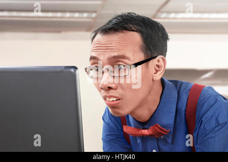 Asian da stupidi imprenditore a lavorare utilizzando il portatile in ufficio Foto Stock
