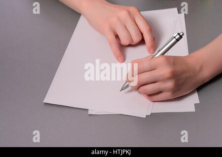 Le mani umane con la scrittura a matita su carta e cancellare la gomma sul tavolo di legno Foto Stock