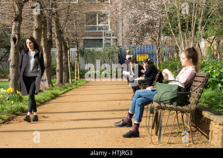 Gli studenti seduti al sole primaverile in Gordon Square, London, Regno Unito Foto Stock