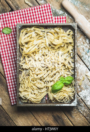 Non cotti pasta italiana nel vassoio di legno su sfondo rustico Foto Stock