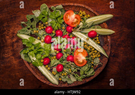 Vista dall'alto di insalata di cetrioli e pomodori verdi su un piatto di legno Foto Stock