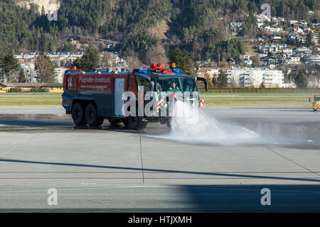 Un aeroporto motore fire la spruzzatura di acqua su per la pista di atterraggio all'aeroporto di Innsbruck, Austria. Foto Stock