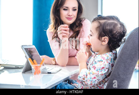 Bella bruna donna alimentazione di sua figlia Foto Stock