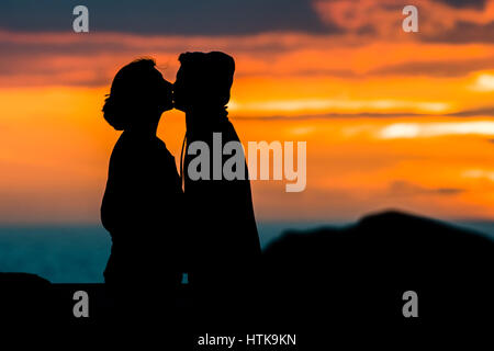 Aberystwyth Wales UK, domenica 12 marzo 2017 UK Meteo: una giovane coppia e abbraccio bacio come dietro di loro il sole tramonta spettacolarmente su acque di Cardigan Bay off Aberystwyth sulla West Wales coast. Photo credit Credito: keith morris/Alamy Live News Foto Stock