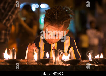 Shwedagon pagoda yangon, myanmar, XII marzo 2017. Un giovane pellegrino imposta una candela in un santuario durante il tabuang luna piena festival. la luna piena è un momento importante per i pellegrini a visitare il Myanmar è più sacra buddista pagoda. tabuang la luna piena è il più promettente e si verifica ogni marzo. Credito: Trevor thompson/alamy live news Foto Stock