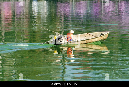 Servizi igienico-sanitari asiatici lavoratore lavora su acqua inquinata da alghe verdi, Vietnamita uomo sedersi sulla barca, inquinamento dell'acqua di fonte è grande problema globale, Vietnam Foto Stock