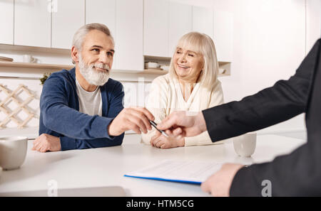 Vecchio carismatico giovane firma accordo a casa Foto Stock