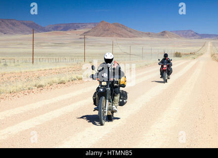 Due motorini guida veloce sul lungo rettilineo di strada nel deserto. Foto Stock