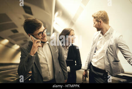 I suoi collaboratori utilizzando le scale della metropolitana insieme per ottenere la metropolitana Foto Stock