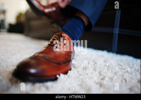 Mani dell'uomo passalacci di legatura della sua nuova marrone scarpe di cuoio. Lo sposo mattina. Foto Stock