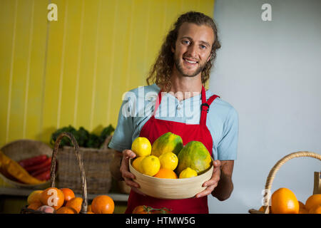 Sorridente personale maschile azienda frutti nel cestello alla sezione biologica del supermercato Foto Stock