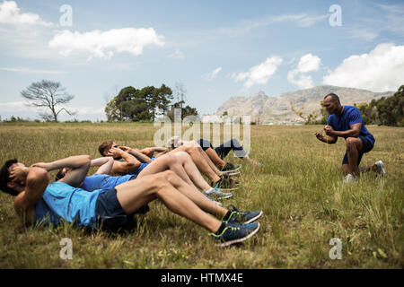 Montare le persone eseguono sgranocchia esercizio in bootcamp Foto Stock