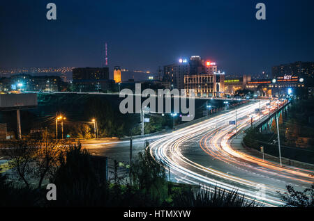 Yerevan, Armenia - 24 Ottobre 2016: vista notturna del Ponte della Vittoria o ponte Haghtanak accesa contro di Yerevan Ararat Brandy-Wine-Vodka Factory Foto Stock