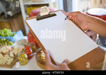 Venditore iscritto negli appunti al bancone del mercato Foto Stock