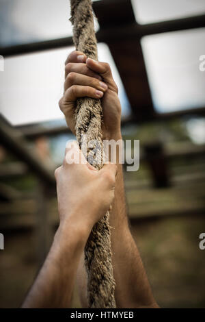 Le mani di uomo salendo una fune durante la corsa a ostacoli Foto Stock