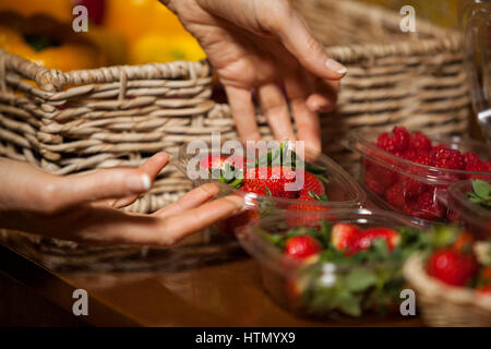 Le mani del personale femminile azienda ciotola di fragole nel supermercato Foto Stock