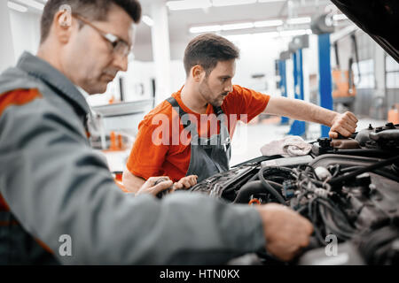 Meccanici a lavorare sulla vettura manutenzione Foto Stock