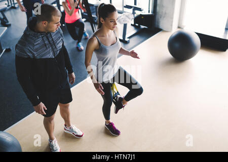 Personal trainer assiste la donna perdere peso in palestra Foto Stock