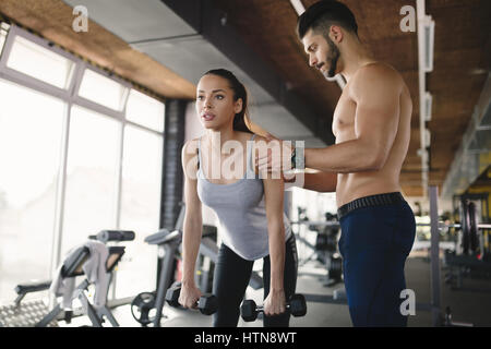 Personal trainer donna aiuta raggiungere gli obiettivi in palestra Foto Stock