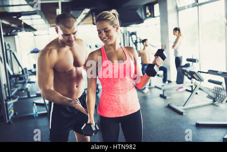 Personal trainer assiste la donna perdere peso in palestra Foto Stock