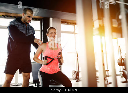 Personal trainer assiste la donna perdere peso in palestra Foto Stock