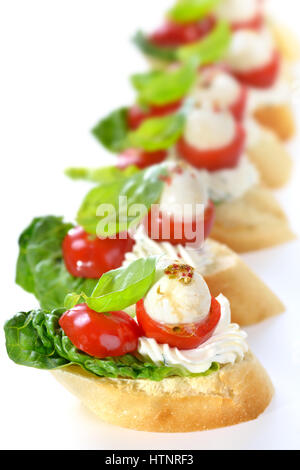 Deliziosi antipasti freddi: fette di baguette con cherry pomodoro, mozzarella, crema di formaggio, olio di oliva e le foglie di basilico Foto Stock