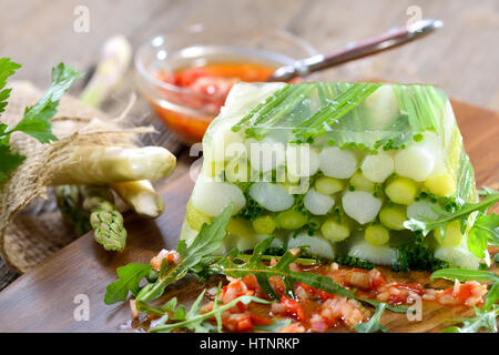 Gelatina di asparagi con carni bianche e verdi Asparagi e erba cipollina, servita con pepe rosso vinaigrette Foto Stock