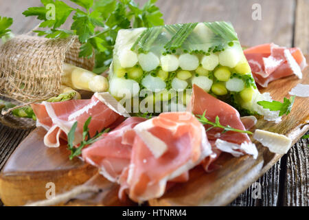 Gelatina di asparagi con carni bianche e verdi Asparagi e erba cipollina, servita con una deliziosa spagnolo il prosciutto Serrano e il parmigiano reggiano Foto Stock